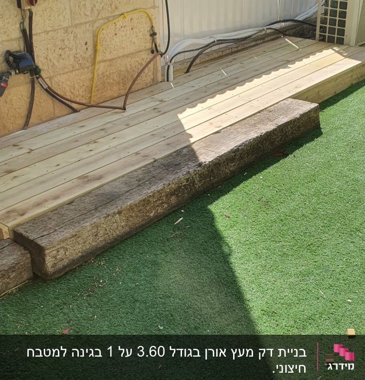 דק עץ ליד דשא סינתטי וגדר לבנה